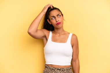 İspanyol güzel kadın şaşkın ve şaşkın hissediyor, başını kaşıyor ve yana bakıyor.