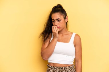 Hispanik güzel kadın ciddi, düşünceli ve endişeli, elleri çenesine bastırılmış şekilde yan bakıyor