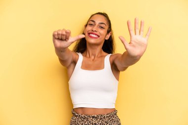 İspanyol güzel kadın gülümsüyor ve arkadaş canlısı görünüyor, altı ya da altıncı numarayı gösteriyor, eli önde, geri sayıyor.