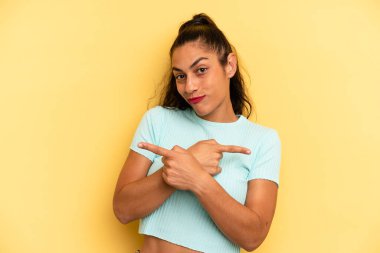 İspanyol güzel kadın şaşkın ve şaşkın görünüyor, güvensiz ve zıt yönlere şüpheyle işaret ediyor.