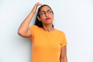 İspanyol güzel kadın şaşkın ve şaşkın hissediyor, başını kaşıyor ve yana bakıyor.