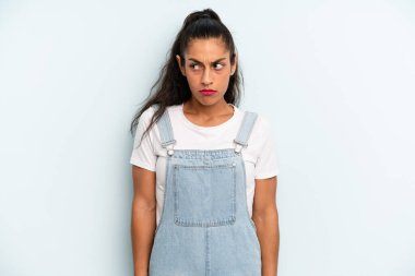 Hispanik güzel kadın üzgün, üzgün ya da kızgın hissediyor ve olumsuz bir tutumla yan yana bakıyor, anlaşmazlık içinde kaşlarını çatıyor