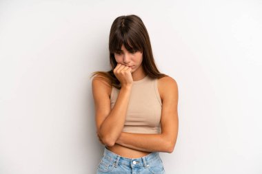 Hispanik güzel kadın ciddi, düşünceli ve endişeli, elleri çenesine bastırılmış şekilde yan bakıyor