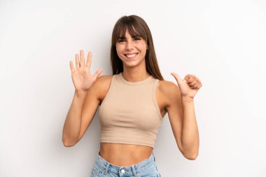 İspanyol güzel kadın gülümsüyor ve arkadaş canlısı görünüyor, altı ya da altıncı numarayı gösteriyor, eli önde, geri sayıyor.