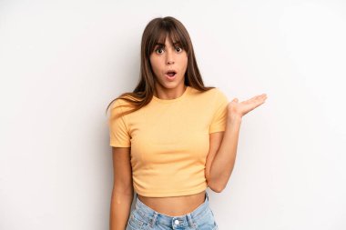 İspanyol güzel kadın şaşırmış ve şoka uğramış görünüyor, çenesi düşmüş, elinde açık bir elle bir nesne tutuyor.