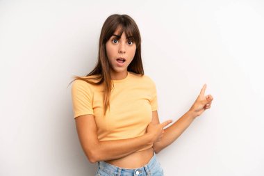 İspanyol güzel kadın şaşkın ve şaşkın hissediyor, kenarda fotokopi alanını işaret ederek, şaşkın, açık ağızlı bir görünüm ile