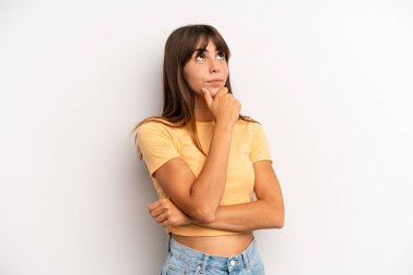 Hispanik güzel kadın düşünceli, meraklı ya da hayal kuruyor, hayal kuruyor ve uzayı kopyalamak için yukarı bakıyor.