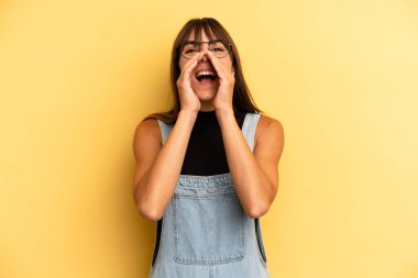 İspanyol güzel kadın mutlu, heyecanlı ve pozitif hissediyor. Elleri ağızda, bağırarak bağırıyor.