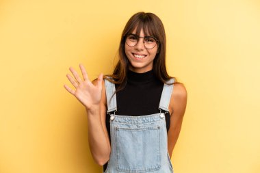 İspanyol güzel kadın gülümsüyor ve arkadaş canlısı görünüyor, 5 ya da 5 numarayı gösteriyor, elleri önde, geriye doğru sayıyor.