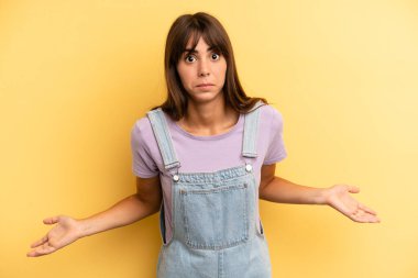 hispanic pretty woman feeling clueless and confused, having no idea, absolutely puzzled with a dumb or foolish look