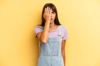 İspanyol güzel kadın uykulu, sıkılmış ve esniyor, baş ağrısı ve yüzünün yarısını kaplayan bir eliyle