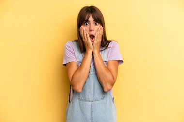 İspanyol güzel kadın şok olmuş ve korkmuş hissediyor, ağzı açık ve elleri yanaklarında korkmuş görünüyor.
