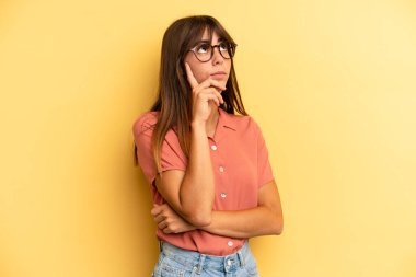 İspanyol bakışlı güzel bir kadın, şüpheli bir ifadeyle merak ediyor, yukarı ve yana bakıyor