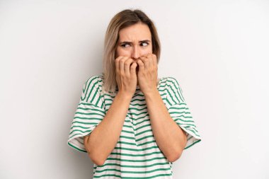 Genç, sarışın kadın endişeli, stresli ve korkmuş görünüyor. Tırnaklarını yiyor ve yanal fotokopi için yer arıyor.