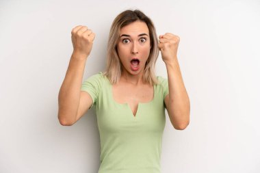 young adult blonde woman celebrating an unbelievable success like a winner, looking excited and happy saying take that!