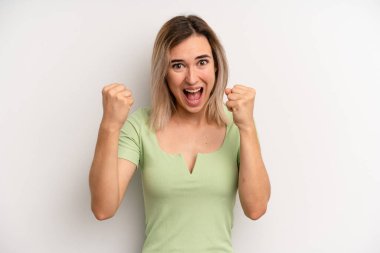 Genç sarışın kadın mutlu, şaşırmış ve gururlanmış hissediyor, bağırıyor ve başarıyı büyük bir gülümsemeyle kutluyor.