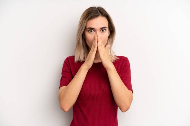 young adult blonde woman feeling worried, upset and scared, covering mouth with hands, looking anxious and having messed up