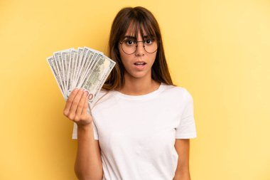 hispanic woman looking very shocked or surprised. dollar banknotes concept