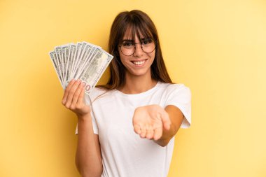 hispanic woman smiling happily with friendly and  offering and showing a concept. dollar banknotes concept