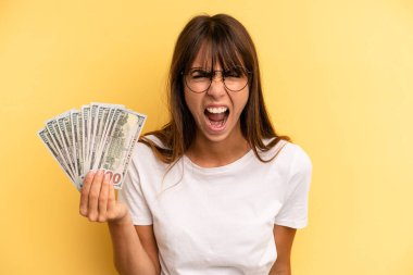 hispanic woman shouting aggressively, looking very angry. dollar banknotes concept