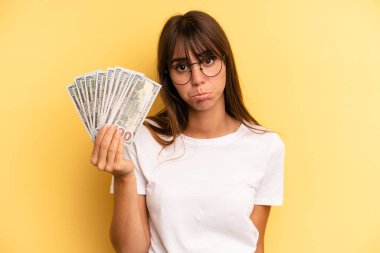 hispanic woman feeling sad and whiney with an unhappy look and crying. dollar banknotes concept