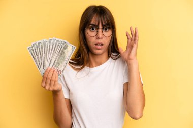 hispanic woman screaming with hands up in the air. dollar banknotes concept