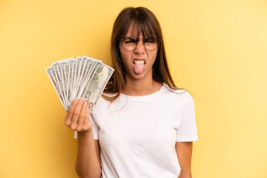 hispanic woman feeling disgusted and irritated and tongue out. dollar banknotes concept