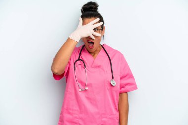 İspanyol kadın şok olmuş, korkmuş ya da dehşete düşmüş görünüyor, yüzünü elleriyle kapatıyor. hemşire konsepti