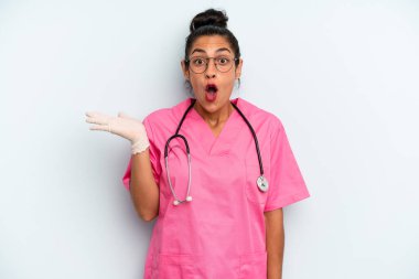 İspanyol kadın şaşırmış ve şok olmuş görünüyor. Çenesi düşmüş ve elinde bir nesne tutuyor. hemşire konsepti