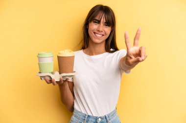 smiling and looking happy, gesturing victory or peace. take away coffees