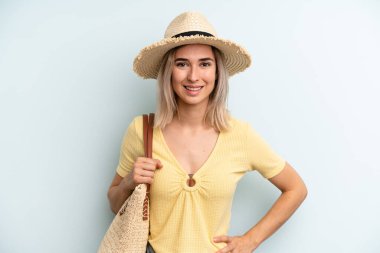 blonde woman smiling happily with a hand on hip and confident. summer concept