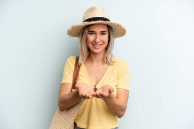 blonde woman smiling happily with friendly and  offering and showing a concept. summer concept