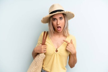 blonde woman looking shocked and surprised with mouth wide open, pointing to self. summer concept