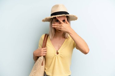 Sarışın kadın şok olmuş, korkmuş ya da korkmuş görünüyor, yüzünü eliyle kapatıyor. yaz konsepti