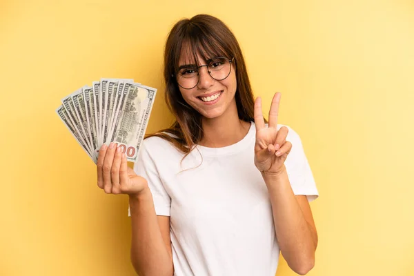 Hispanic Woman Smiling Looking Friendly Showing Number Two Dollar Banknotes — Foto Stock