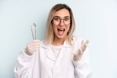 blonde woman feeling happy and astonished at something unbelievable. dentist concept