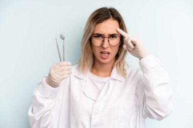 Sarışın kadın şaşkın ve şaşkın hissediyor, senin deli olduğunu gösteriyor. dişçi kavramı