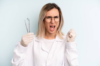 Kızgın bir ifadeyle bağıran sarışın kadın. dişçi kavramı