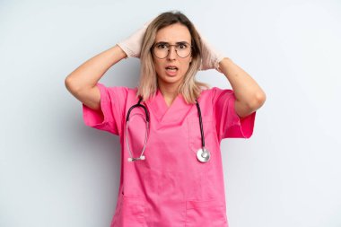 Sarışın kadın kendini stresli, endişeli ya da korkmuş hissediyor, elleri başının üstünde. hemşire konsepti