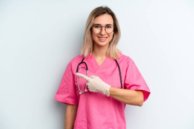 Sarışın kadın neşeyle gülümsüyor, mutlu hissediyor ve bir tarafı işaret ediyor. hemşire konsepti