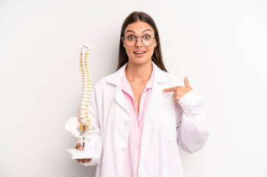 Güzel bir kadın mutlu hissediyor ve heyecanla kendini işaret ediyor. Omurga uzmanı konsepti