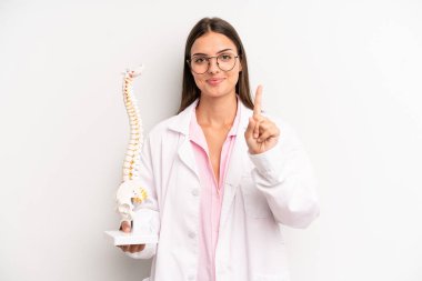 Güzel bayan gülümsüyor ve arkadaş canlısı görünüyor, bir numarayı gösteriyor. Omurga uzmanı konsepti