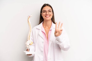 Güzel bayan gülümsüyor ve arkadaş canlısı görünüyor, üç numarayı gösteriyor. Omurga uzmanı konsepti