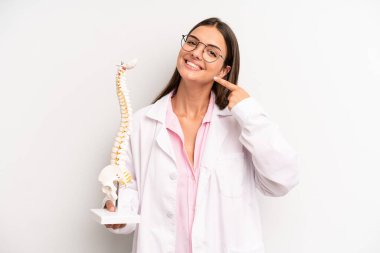 Kendine güvenen güzel bir kadın kendi gülüşünü işaret ediyor. Omurga uzmanı konsepti