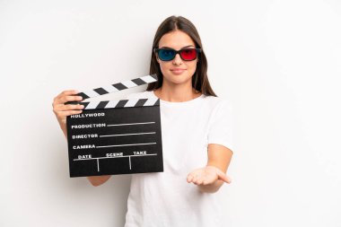 Güzel bir kadın mutlu bir şekilde gülümsüyor ve bir konsept sunuyor. film veya film konsepti