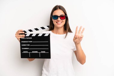 Güzel bayan gülümsüyor ve arkadaş canlısı görünüyor, üç numarayı gösteriyor. film veya film konsepti