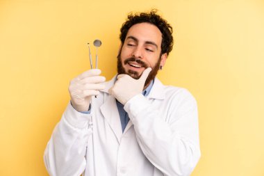 Genç adam mutlu, kendinden emin ve elleri çenesinde gülümsüyor. dişçi kavramı