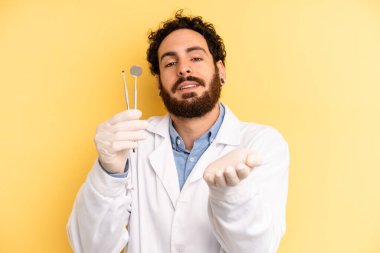 Genç adam arkadaşça gülümsüyor ve bir konsept sunuyor. dişçi kavramı