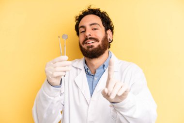 Genç adam gururla gülümsüyor ve kendinden emin bir numara oluyor. dişçi kavramı