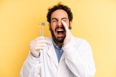 Genç adam kendini mutlu hissediyor, elleri ağzının kenarında bağırarak bağırıyor. dişçi kavramı